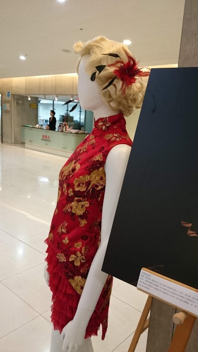 Mannequin wearing blond finger wave wig and qipao with dramatic cut in an exhibition.